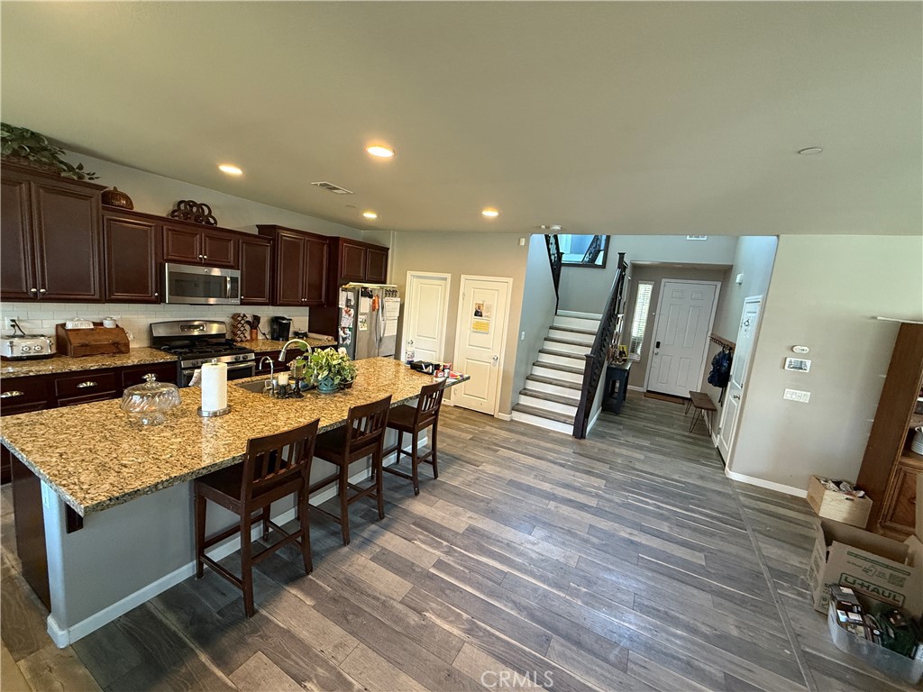 30130 Pine Needle Road Menifee, CA 92585 - Photo 39 of 45 a kitchen with stainless steel appliances granite countertop a refrigerator oven a sink dishwasher and white cabinets with wooden floor