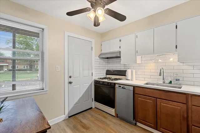 a kitchen with stainless steel appliances granite countertop a sink a stove a refrigerator cabinets and a window