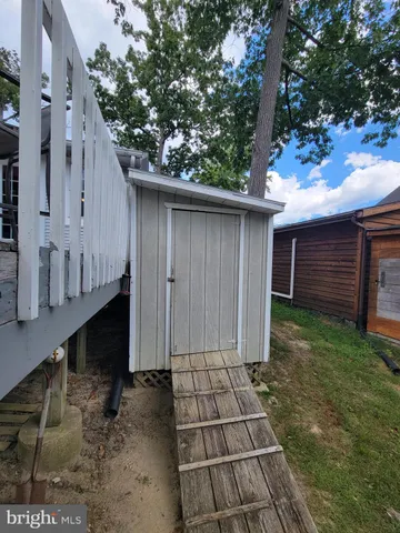 a view of backyard of house with wooden deck and large tree