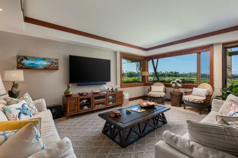 a living room with furniture a flat screen tv and floor to ceiling window