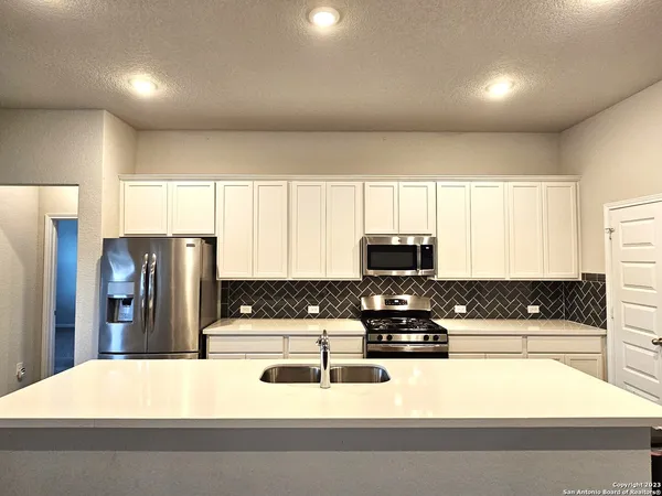 a kitchen with stainless steel appliances kitchen island granite countertop a refrigerator and a stove top oven