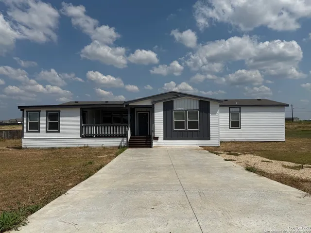 a front view of house with yard and trees in the background