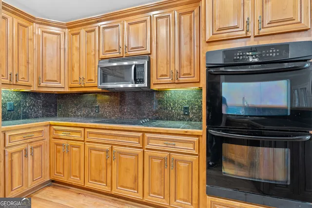 a kitchen with stainless steel appliances granite countertop a refrigerator a oven and white cabinets with wooden floors