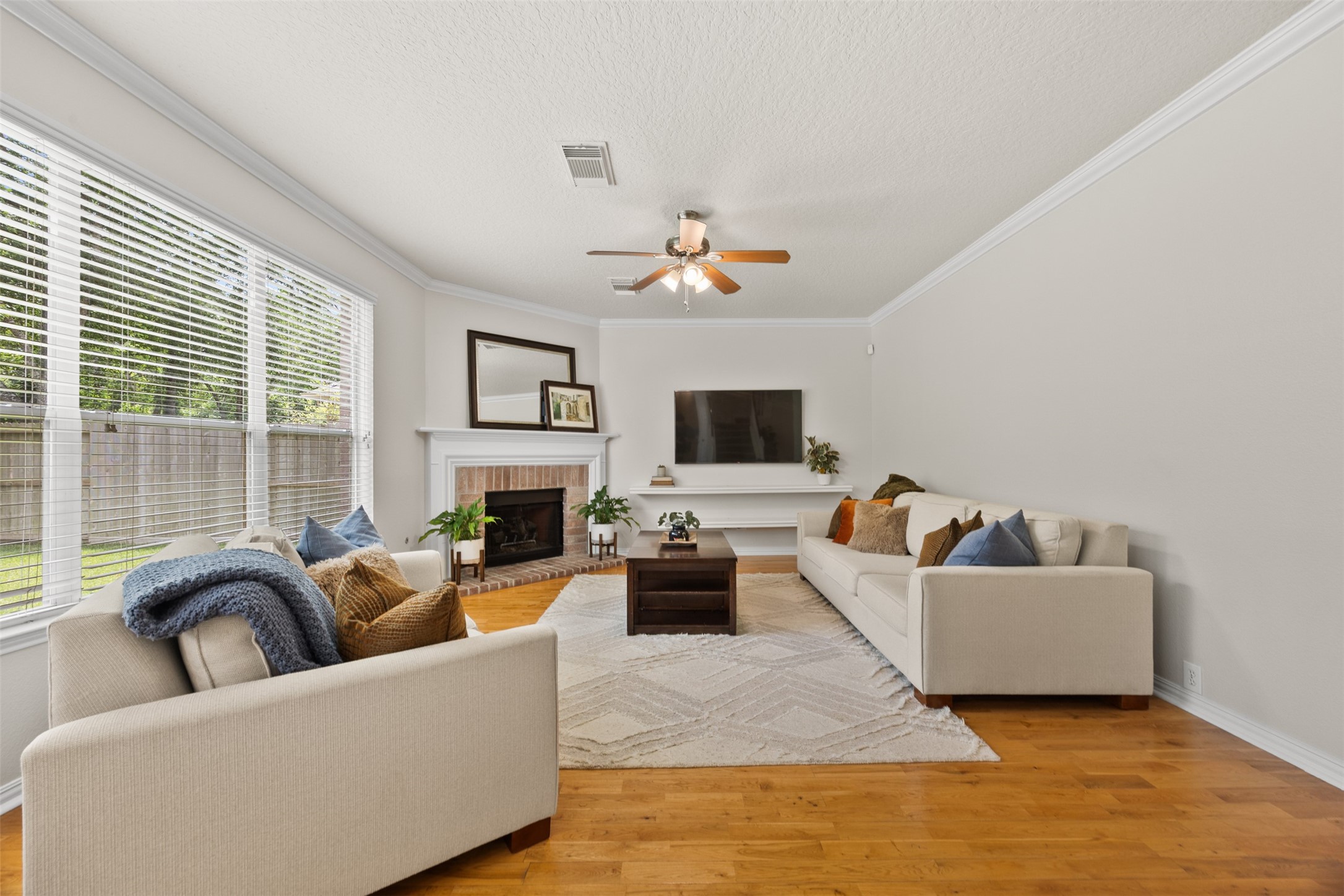2219 Louetta Brook Lane Spring, TX 77388 - Photo 20 of 34 Inviting living room with hardwood floors, large windows for natural light, and a cozy brick fireplace as the focal point.