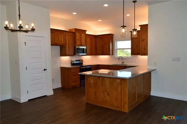 a kitchen with stainless steel appliances granite countertop a sink a stove and a wooden floor