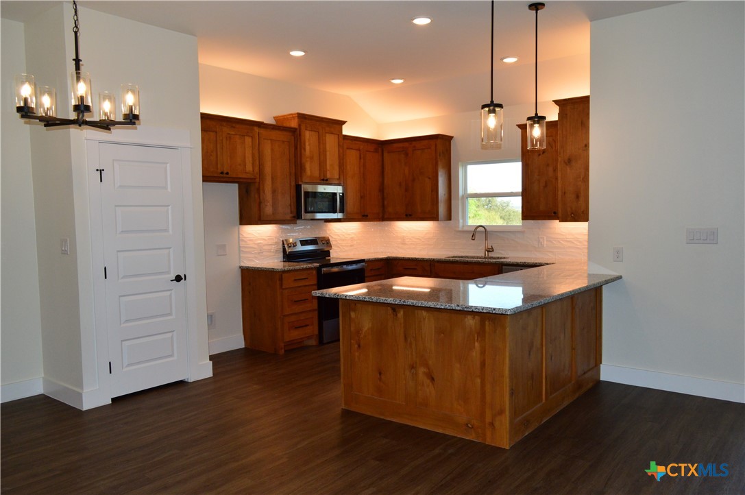 425 County Road 3152 Kempner, TX 76539 - Photo 13 of 48 a kitchen with stainless steel appliances granite countertop a sink a stove and a wooden floor