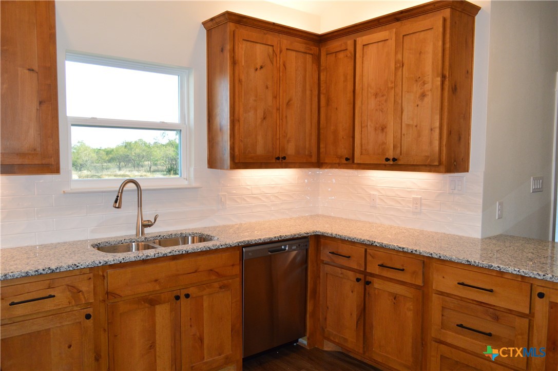 425 County Road 3152 Kempner, TX 76539 - Photo 17 of 48 a kitchen with granite countertop wooden cabinets a sink and a window