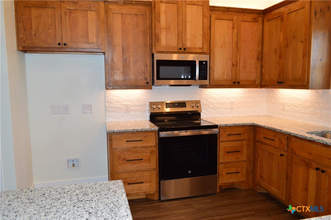 425 County Road 3152 Kempner, TX 76539 - Photo 18 of 48 a kitchen with granite countertop a stove and a microwave with wooden floor
