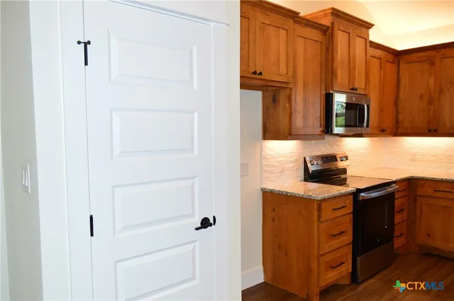 a kitchen with stainless steel appliances granite countertop a refrigerator and a stove top oven