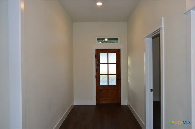 a view of hallway with window and wooden floor
