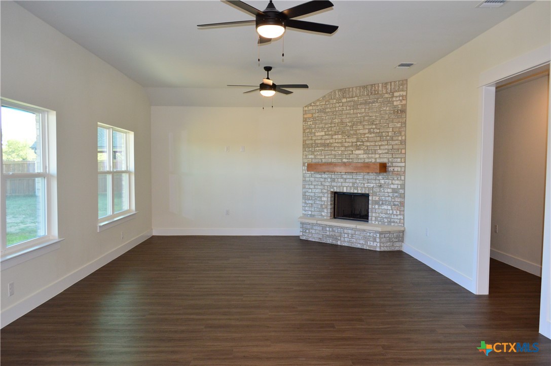 425 County Road 3152 Kempner, TX 76539 - Photo 6 of 48 an empty room with wooden floor a ceiling fan a fireplace and windows