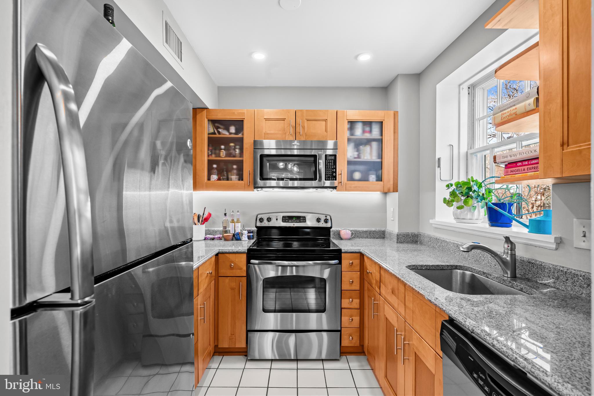 3861 Porter Street Northwest, Unit C285 Washington, DC 20016 - Photo 9 of 23 a kitchen with stainless steel appliances granite countertop a stove a sink and a refrigerator