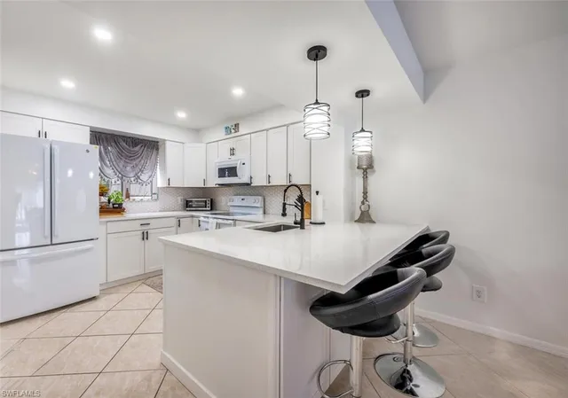 a kitchen with a sink a refrigerator and chairs