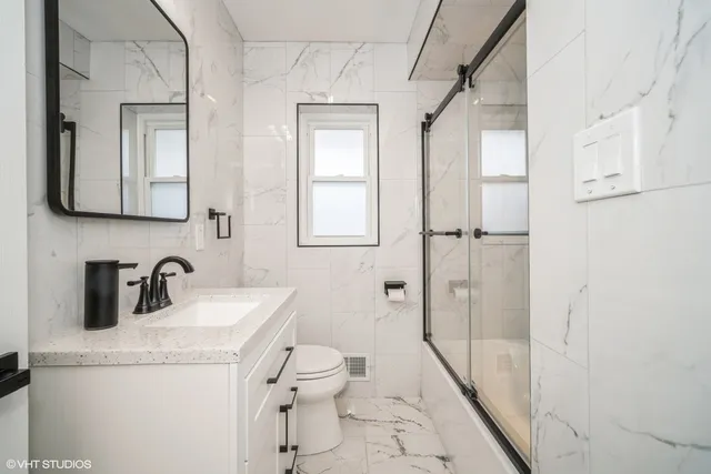 a bathroom with a granite countertop sink toilet and shower glass door