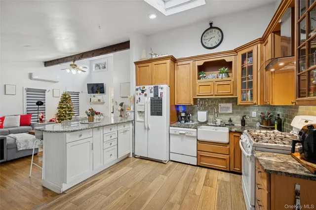 a kitchen with stainless steel appliances granite countertop a stove a sink dishwasher and white cabinets with wooden floor
