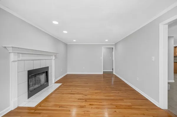 a view of an empty room with a fireplace and wooden floor