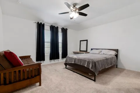a spacious bedroom with a bed window and a chandelier