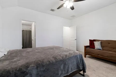 a spacious bedroom with a bed and a ceiling fan