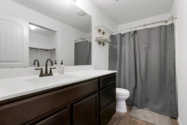 a bathroom with a sink a toilet a mirror and shower