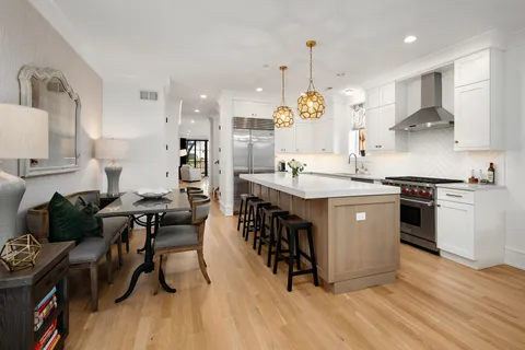 a kitchen with stainless steel appliances granite countertop a stove a sink dishwasher a refrigerator and white cabinets with wooden floor