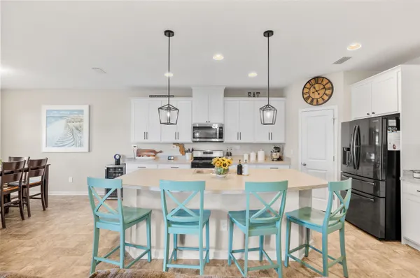 a kitchen with stainless steel appliances granite countertop a dining table chairs and white cabinets