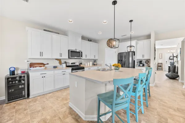 a kitchen with stainless steel appliances kitchen island granite countertop a sink a stove a dining table and chairs