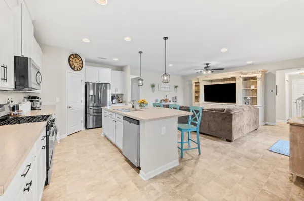 a large white kitchen with stainless steel appliances kitchen island granite countertop a stove and a sink