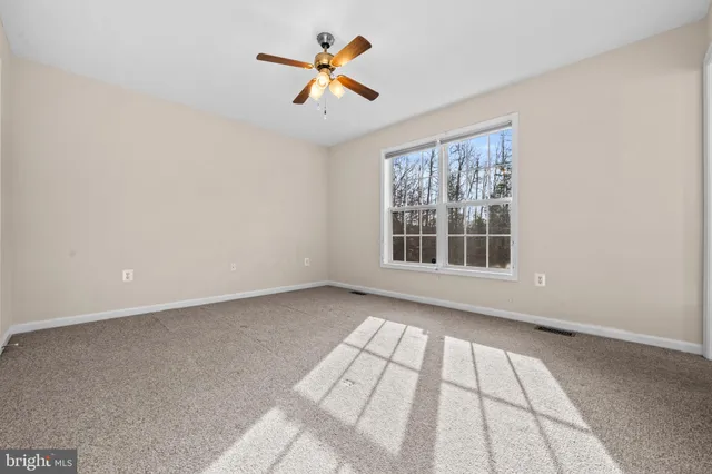 an empty room with windows and ceiling fan