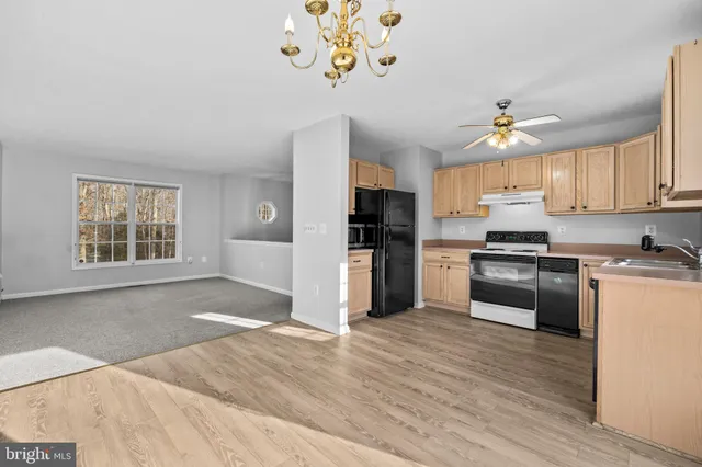 a kitchen with granite countertop a stove a sink dishwasher and a refrigerator with wooden floor