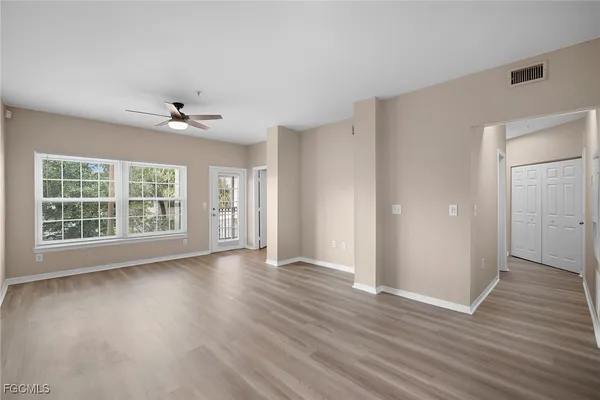 a view of an empty room with a window and wooden floor