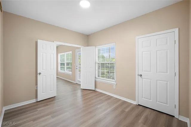 an empty room with wooden floor and windows
