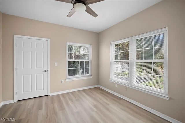 a view of an empty room with a window and wooden floor