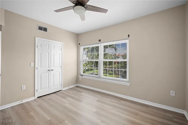 a view of an empty room with a window and wooden floor