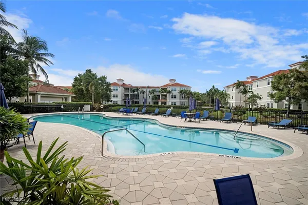 a view of a swimming pool with a lounge chair and palm trees