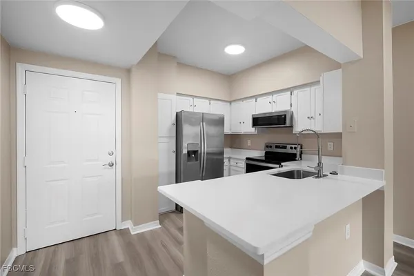 a kitchen with a refrigerator a microwave a sink and cabinets