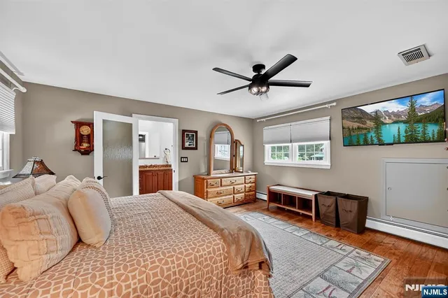 a bedroom with a large bed a flat tv screen and dresser