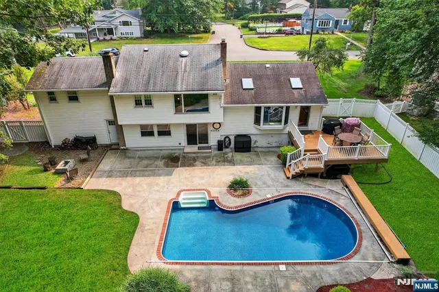 a view of a house with swimming pool lawn chairs and a small yard