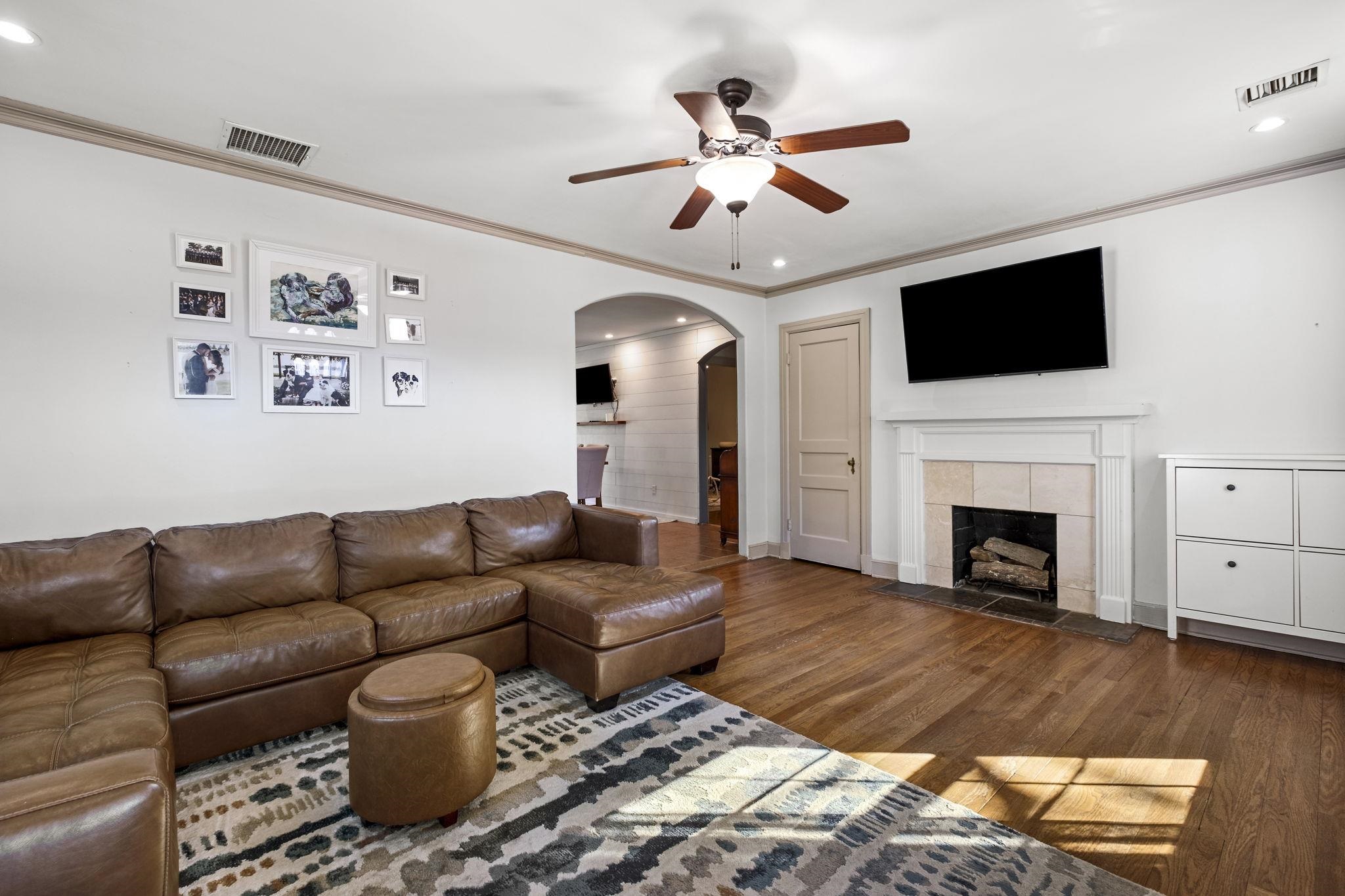 4120 Village Road Memphis, TN 38117 - Photo 6 of 28 Living area featuring a fireplace, arched walkways, ceiling fan, wood finished floors, and crown molding