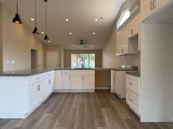 a large kitchen with granite countertop a large counter top a sink stainless steel appliances and cabinets
