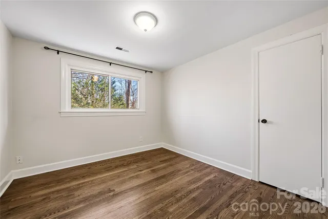 an empty room with wooden floor and window