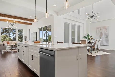 a dining room with wooden floor a chandelier a glass table and chairs