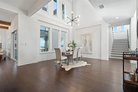 a dining room with wooden floor a chandelier a glass table and chairs