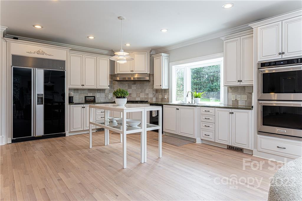 343 Vanderbilt Road Asheville, NC 28803 - Photo 12 of 48 a kitchen with stainless steel appliances granite countertop a stove top oven a sink a refrigerator with white cabinets and wooden floor