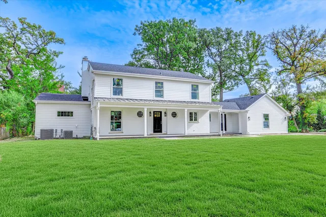 a white house with a big yard and large trees