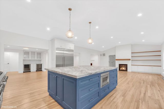 a kitchen with stainless steel appliances granite countertop a large counter top a sink and a wooden floors