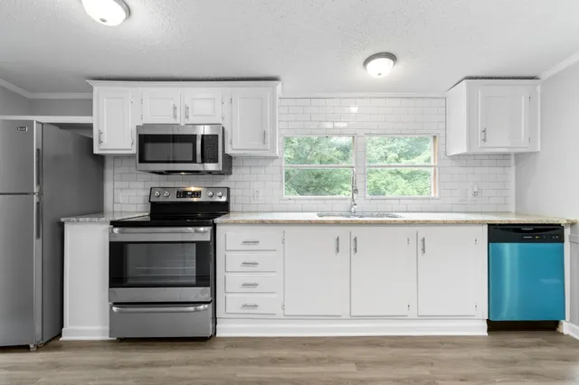a kitchen with white cabinets stainless steel appliances and a window