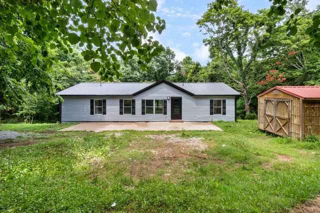 a aerial view of a house next to a yard with potted plants and large tree