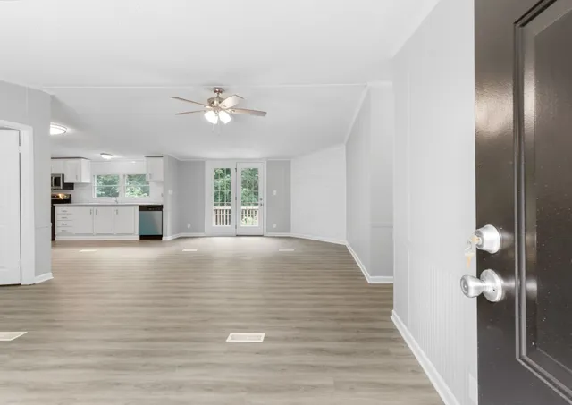 a view of an empty room with kitchen and window
