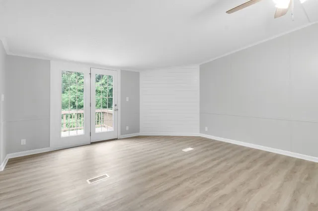 a view of an empty room with wooden floor and a window