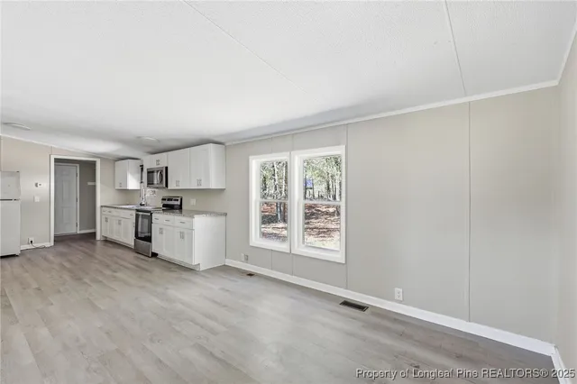 a kitchen with stainless steel appliances granite countertop a refrigerator a stove top oven a sink dishwasher and white cabinets with wooden floor